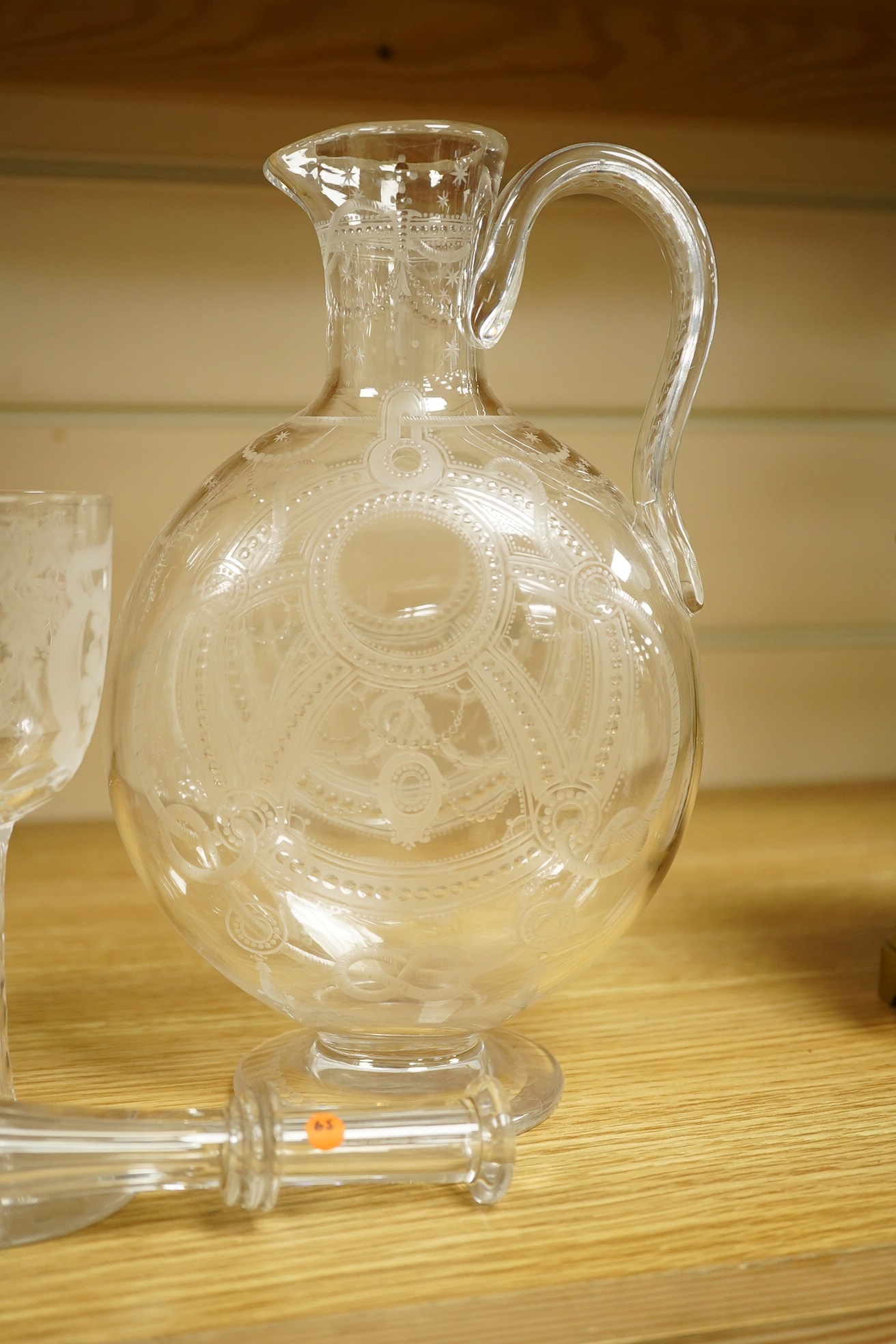 A Continental Art Nouveau glass carafe enamelled with flowers, an English wine glass engraved with the symbols of the Union, a Victorian engraved claret jug and a toddy lifter. Condition - carafe has some occasional scra